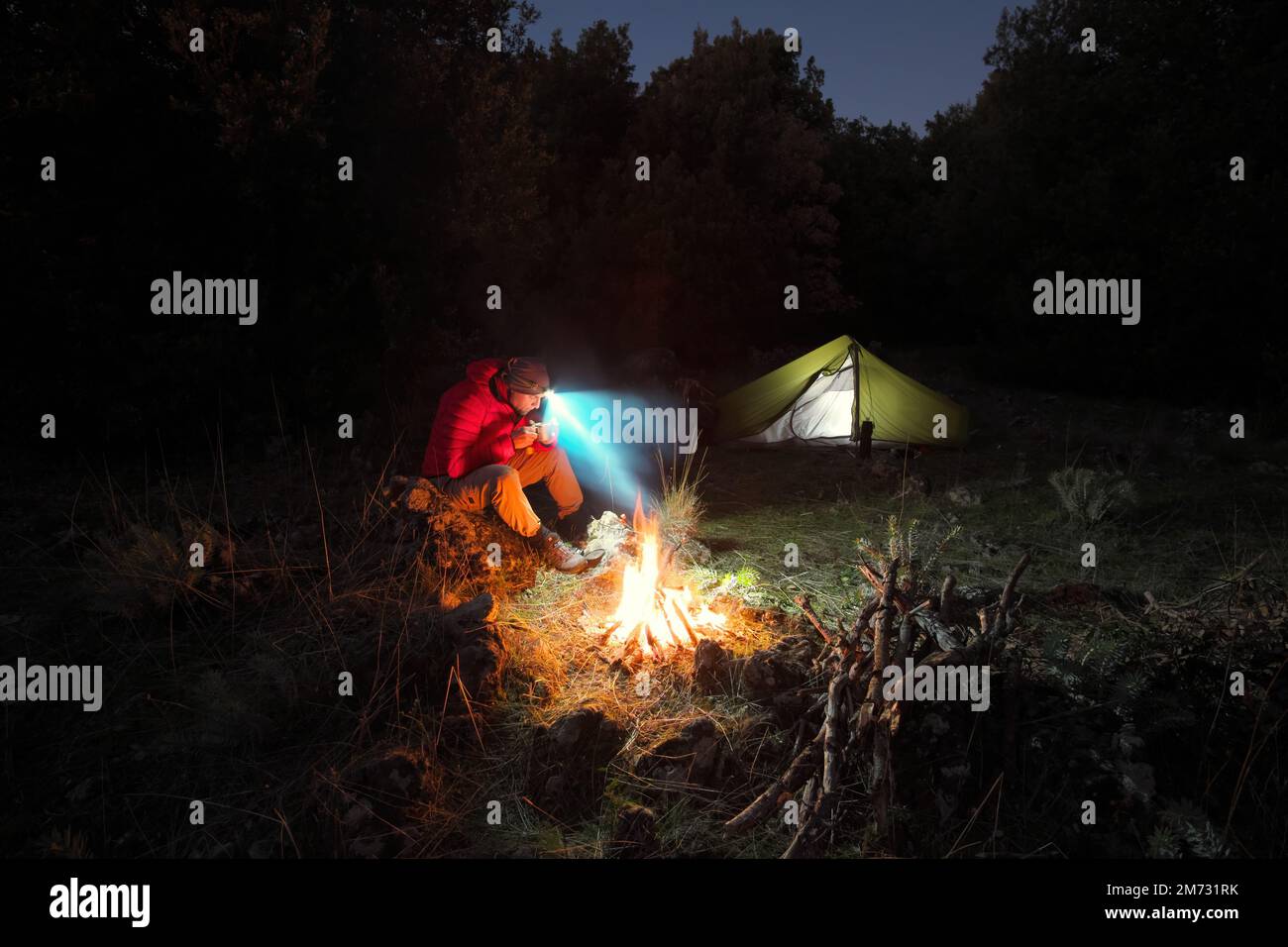 Homme assis près du feu de camp en Sicile la nuit, Etna Park, Italie Banque D'Images