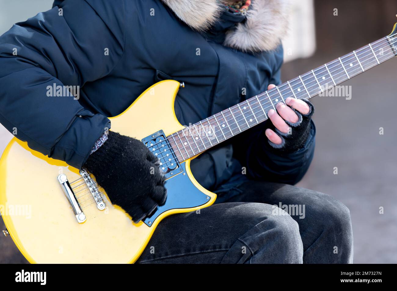 Gros plan de la main mâle guitariste dans un gant noir qui touche la corde  sur la guitare jaune à six cordes, musicien de rue Photo Stock - Alamy