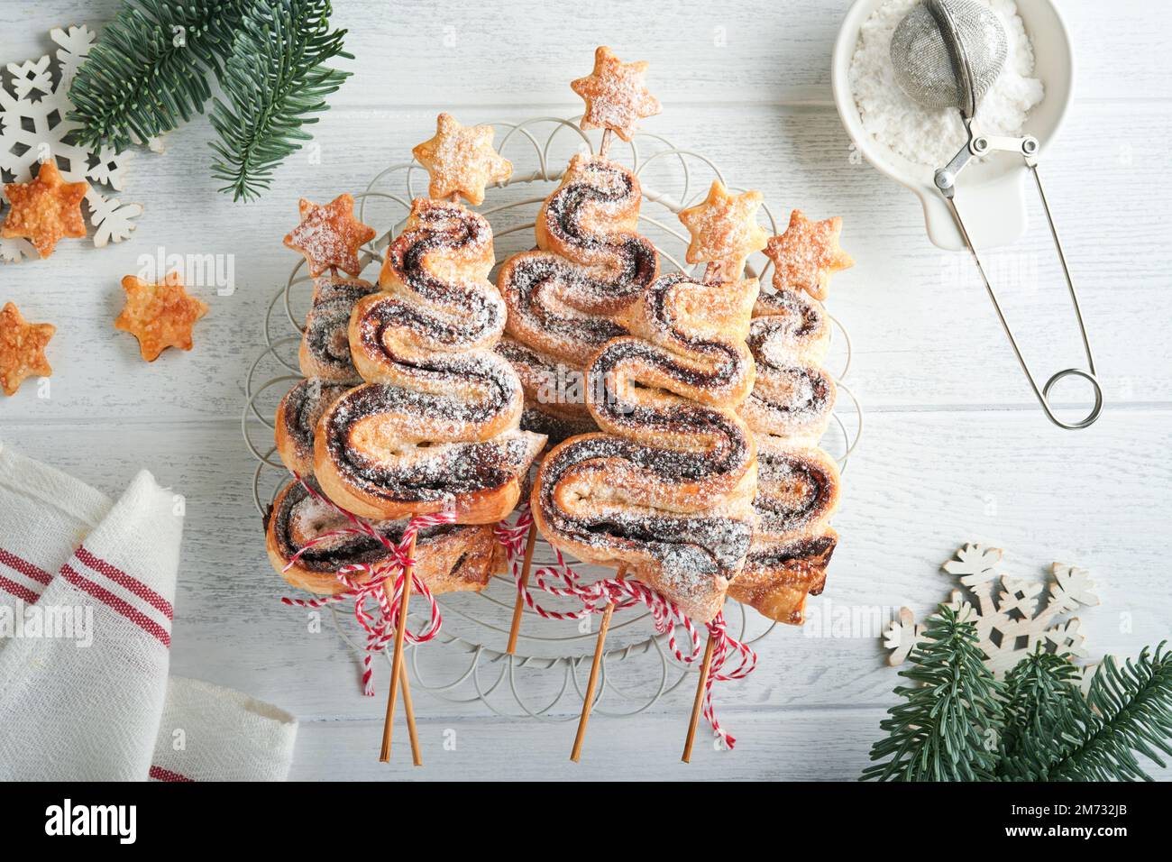 Gâteau feuilleté en forme d'arbre de Noël avec garniture au chocolat, poudre de sucre et sucettes sur fond de bois blanc ancien. Noël, nouvel an Banque D'Images