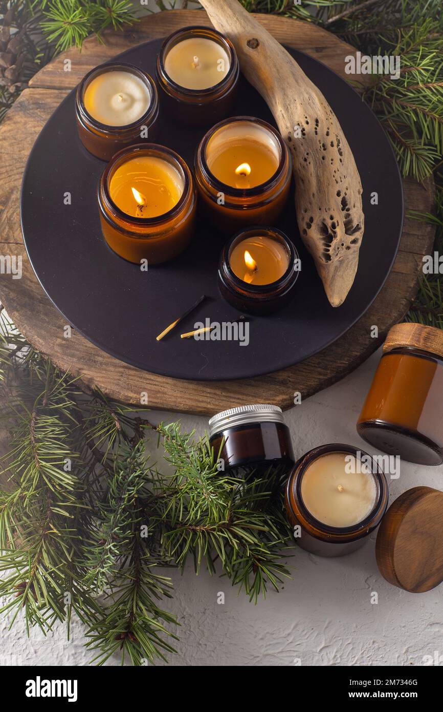 Les bougies de soja brûlent dans des pots en verre. Confort à la maison. Bougie dans un pot brun. Parfum et lumière. Bougie parfumée faite à la main. Aromathérapie. Arbre de Noël et ambiance d'hiver. Décoration chaleureuse. Décoration de fête Banque D'Images