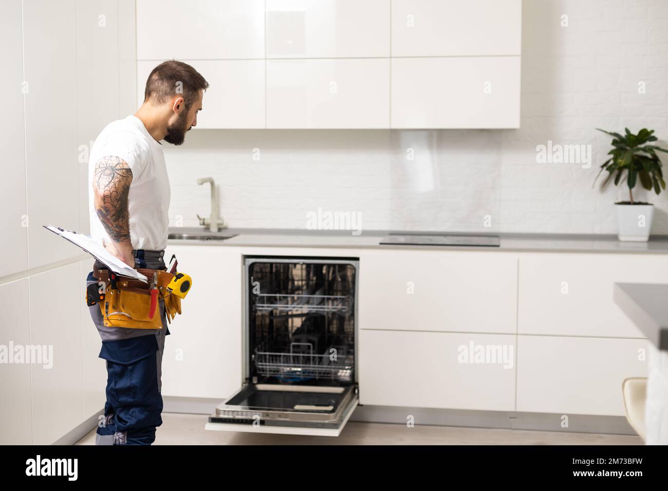 Les jeunes travailleurs Service réparateur réparation lave-vaisselle  appareil dans la cuisine Photo Stock - Alamy