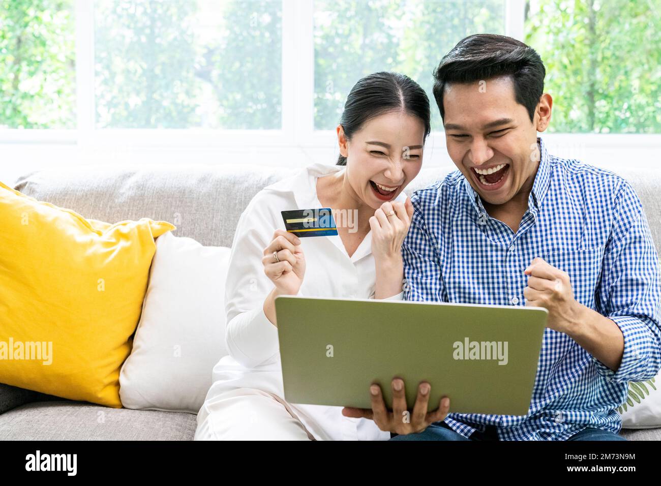 Les jeunes couples asiatiques utilisent la carte de crédit pour faire des achats sur Internet dans la salle de séjour à la maison Banque D'Images