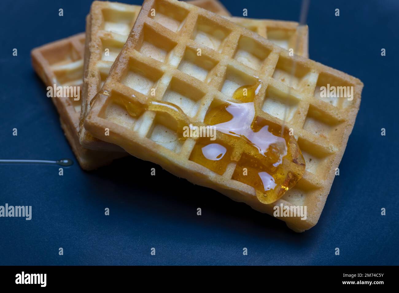 gaufres sur une assiette bleue tout en étant garni de miel Banque D'Images