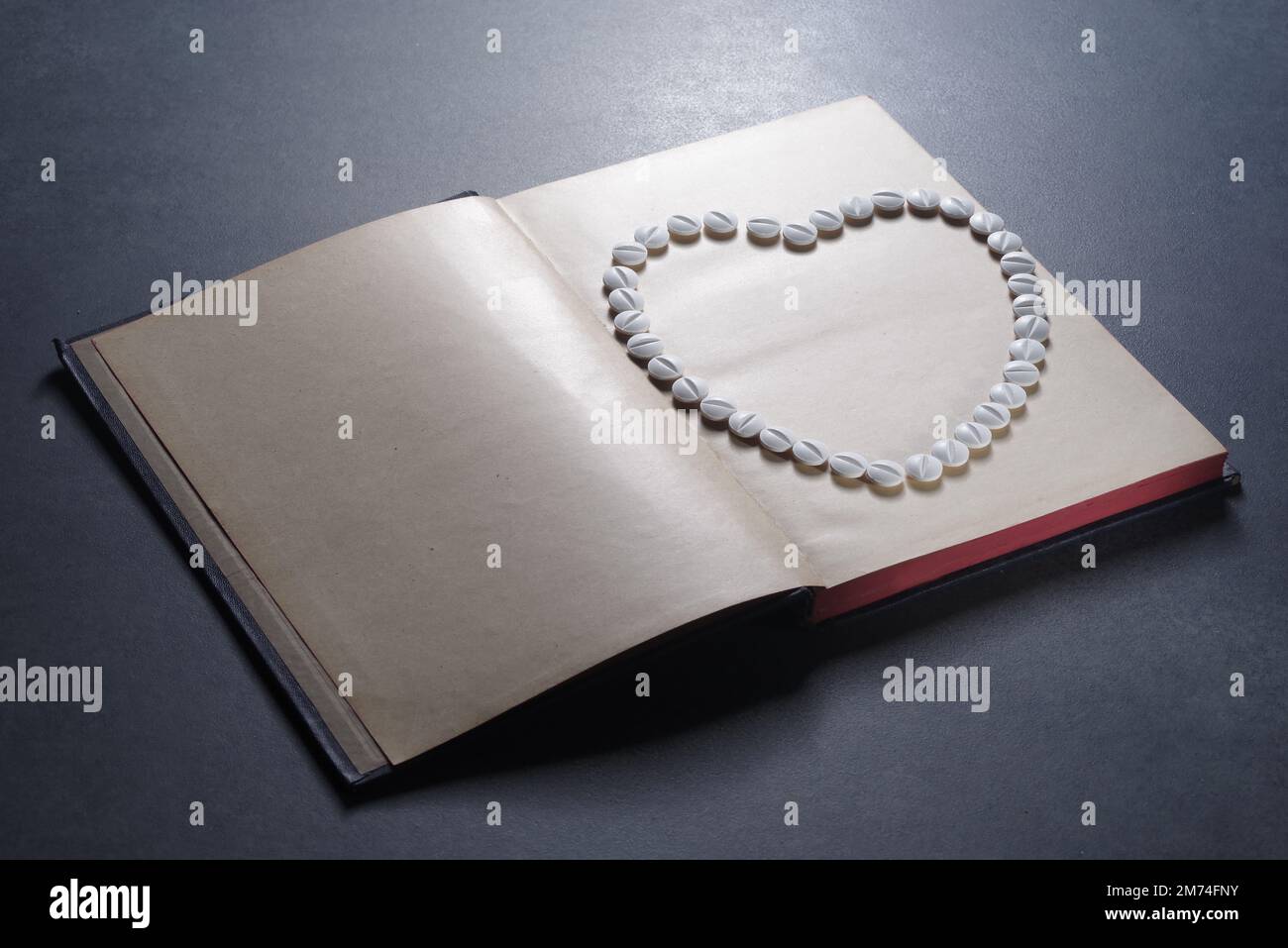 Symbole de coeur disposé à partir de pilules sur un livre. Droit en médecine. Concept de droit médical et de crimes médicaux Banque D'Images