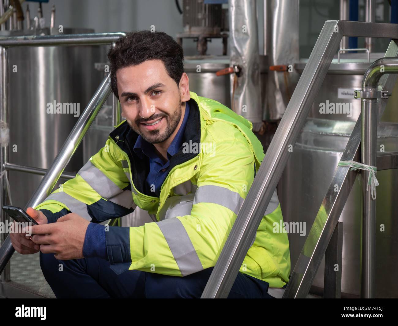 Portrait d'un ingénieur d'usine souriant utilisant une tablette numérique dans la chaîne de production de l'usine de boissons. Employé d'usine contrôlant la production. Banque D'Images