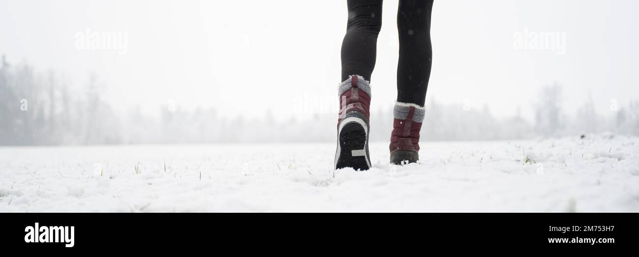 Image grand angle de vue basse des jambes de femmes en hiver bottes marchant dans la neige nature couverte. Banque D'Images