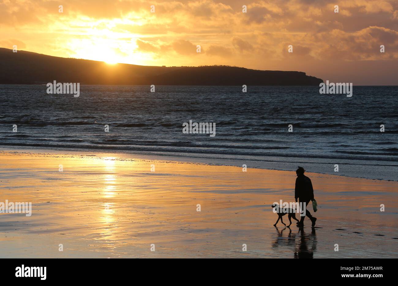 Ayr, Ayrshire, Écosse. UK Jan 2023 .Une figure silhouettée e avec le chien aime une promenade en soirée le long de la plage à Ayr comme l'espace de couchers de soleil pour la copie ou le texte. Image romantique de style de vie Banque D'Images