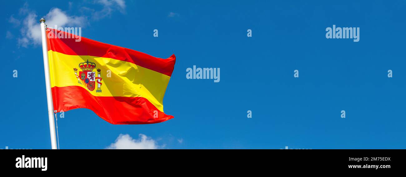 Drapeau de l'Espagne agitant dans le vent sur le mât contre le ciel avec des nuages le jour ensoleillé, bannière, gros plan Banque D'Images