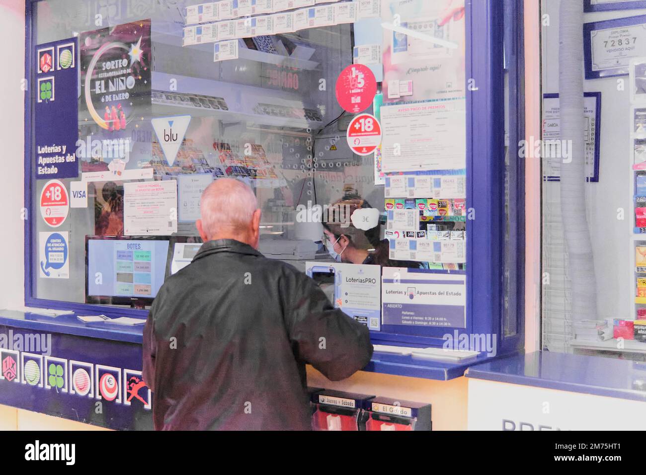 Ténérife, Espagne - 07 janvier 2023: Personne âgée méconnaissable devant un stand de loterie achetant des billets de loterie fréquentés par une femme Banque D'Images