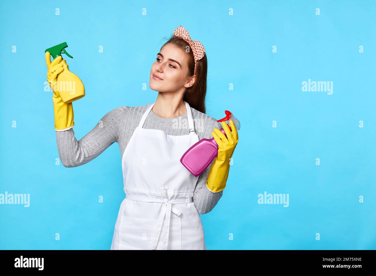 femme en gants de caoutchouc choisit entre deux produits de nettoyage Banque D'Images