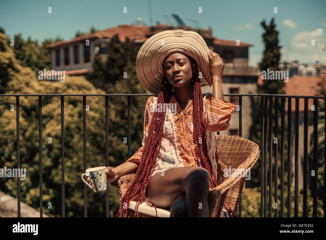 Une capture colorée d'une jeune fille d'origine afro-descendante, habillée féministe, dans une robe à fleurs rose et orange, chapeau à large bord et cheveux longs, Banque D'Images