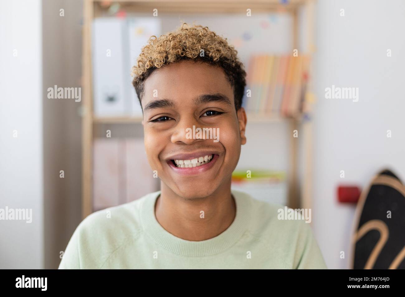 Jeune adolescent latino-américain souriant regardant l'appareil photo à l'intérieur Banque D'Images