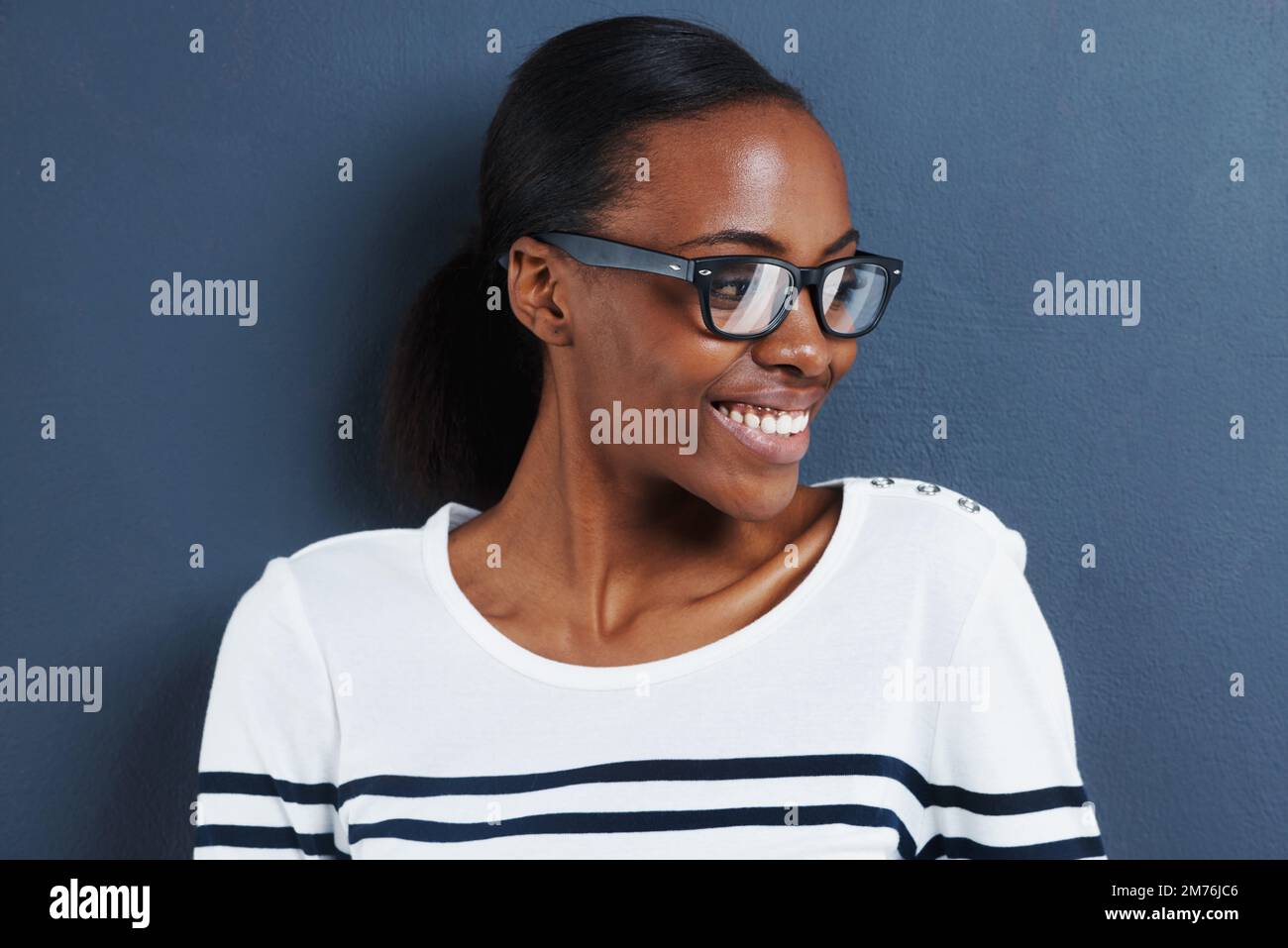 J'aime ça. une jeune femme attrayante portant des lunettes regardant sur le côté sur un fond gris. Banque D'Images