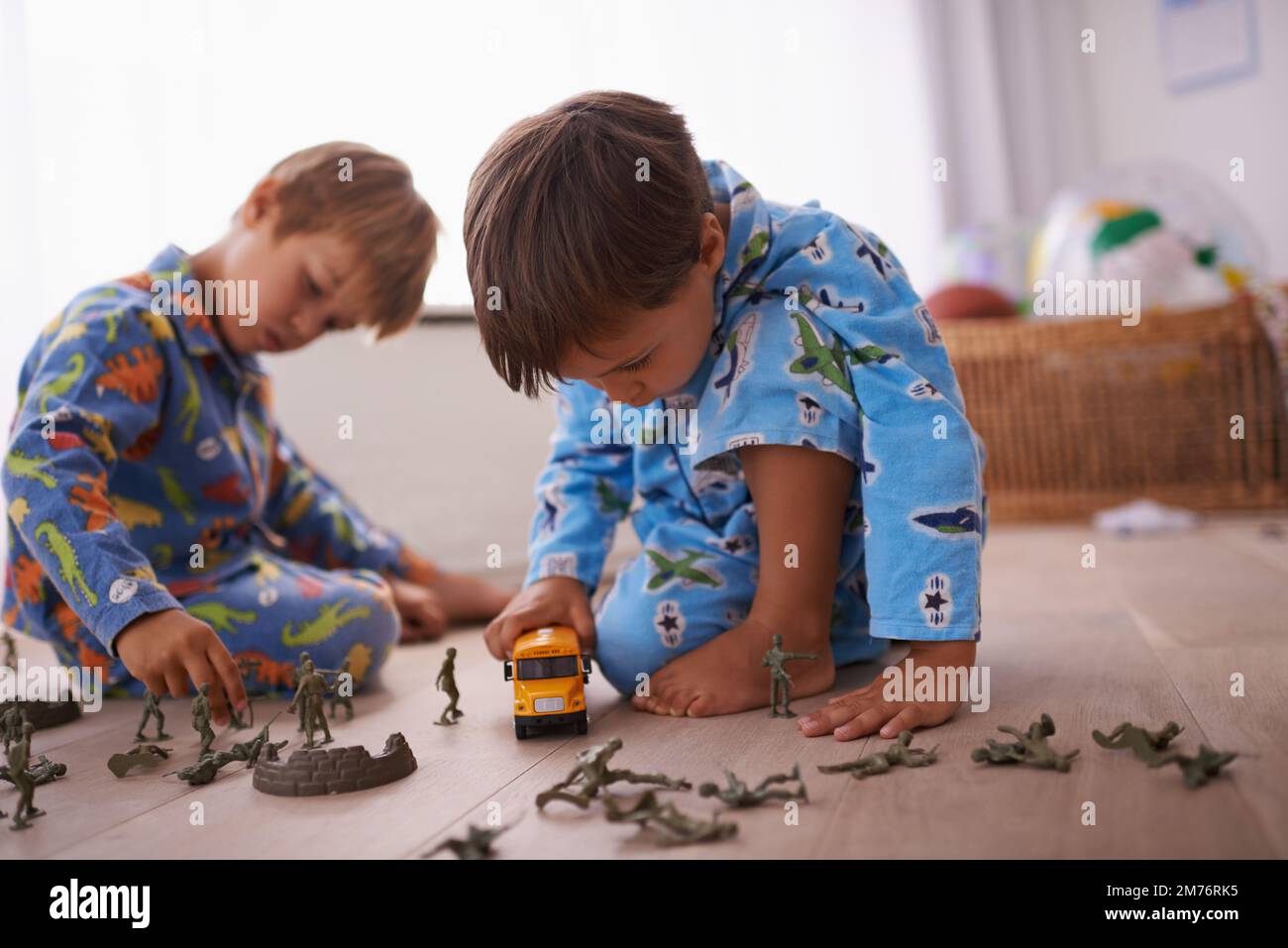 Je suis loin de tout ce drame. deux petits garçons jouant avec leurs jouets sur le sol. Banque D'Images