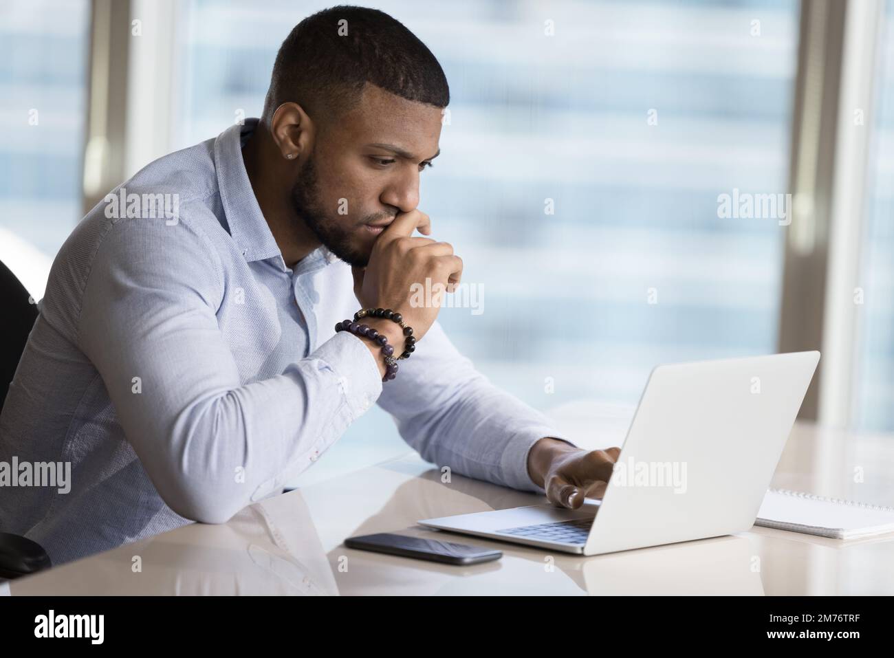 Un homme d'affaires africain apprend de nouveaux logiciels, travaillant sur un ordinateur portable d'utilisation de projet Banque D'Images