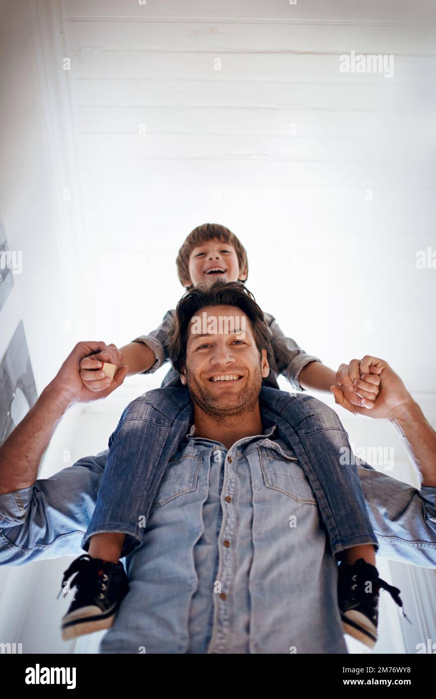Forger un lien solide. Portrait d'un père portant son fils sur ses épaules à la maison. Banque D'Images