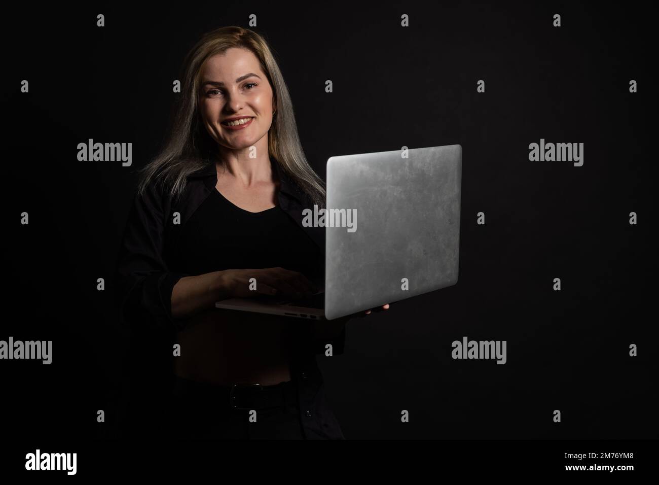 femme avec ordinateur portable sur fond noir Banque D'Images