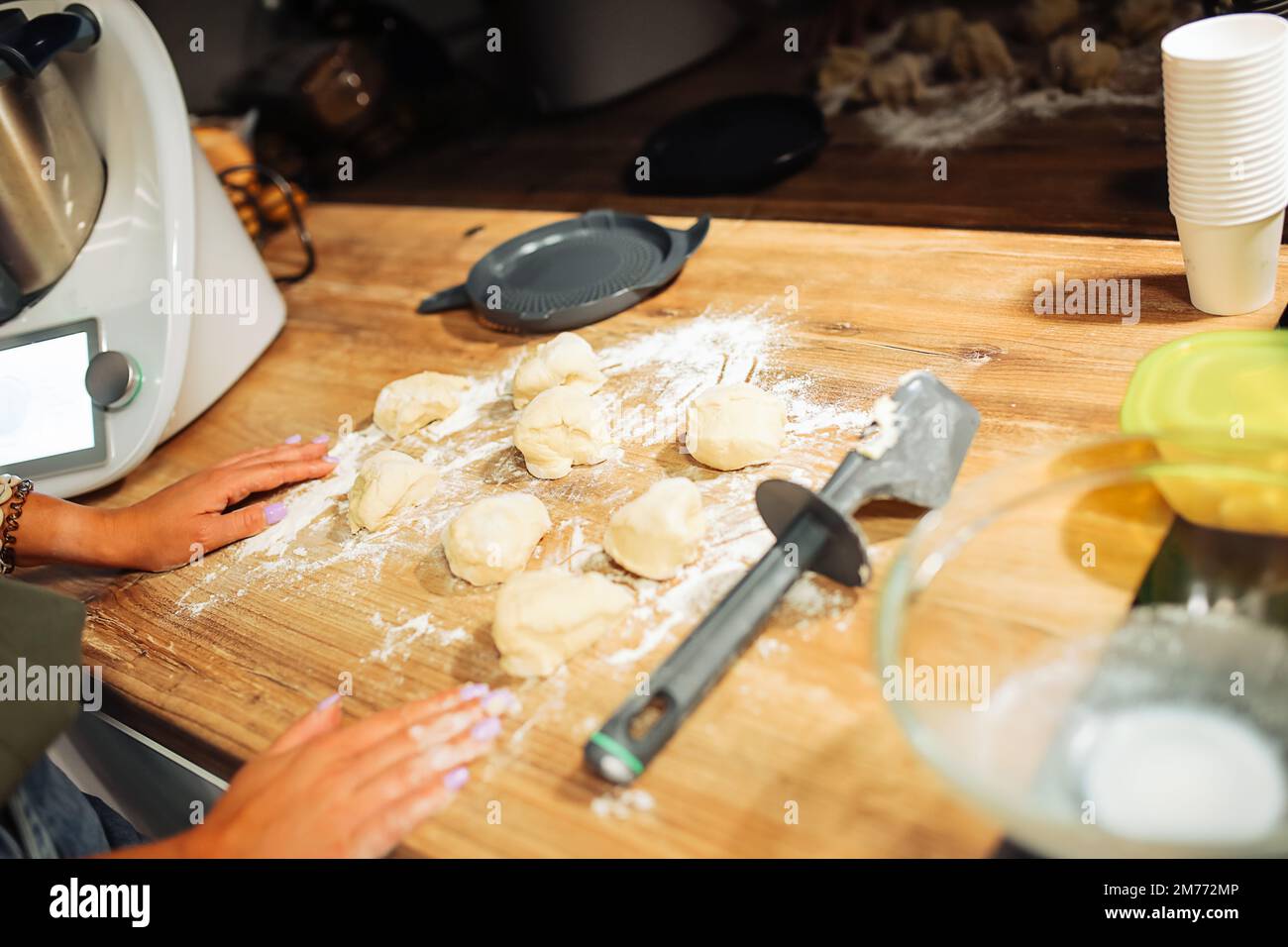 Disposition d'un morceau de pâte brute de forme ronde sur un comptoir en bois. Couper la pâte en morceaux à l'aide d'un couteau. Dessert maison. Banque D'Images