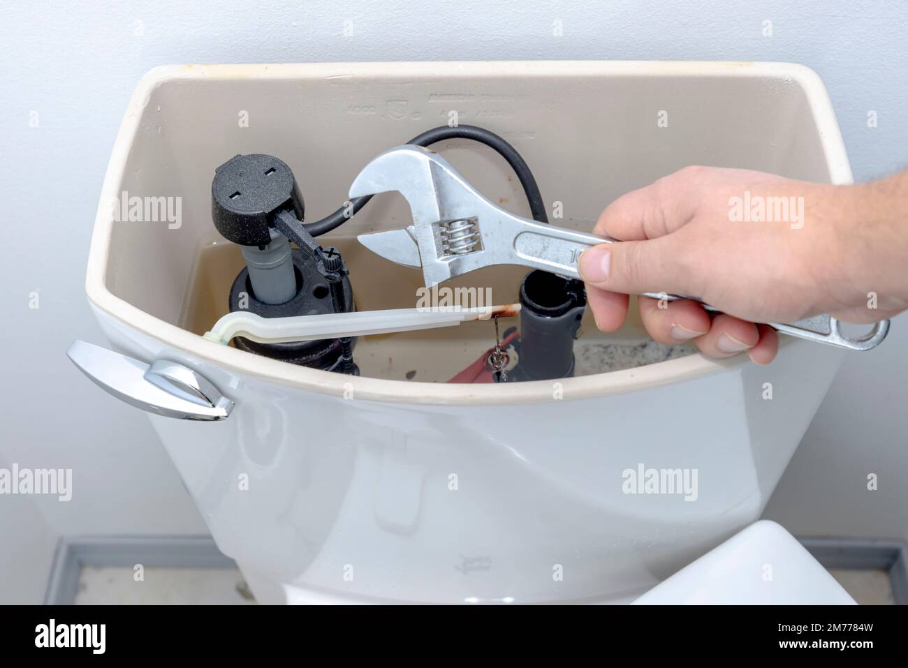 Une personne tenant une clé réglable avec un réservoir ouvert exposant la soupape intérieure et le levier. Banque D'Images