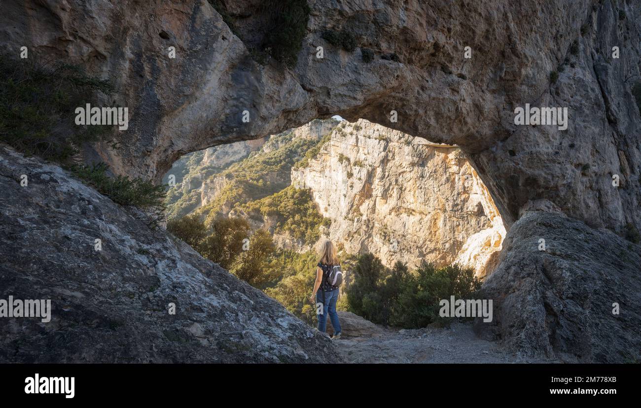 Femme regardant à travers l'Arche naturelle Forat de la Vella au Parc naturel de ports de Beseit, Catalogne Banque D'Images