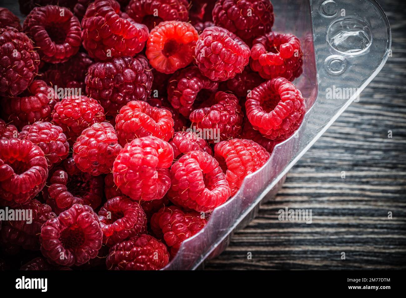 Framboise rouge dans un récipient sur bois. Banque D'Images