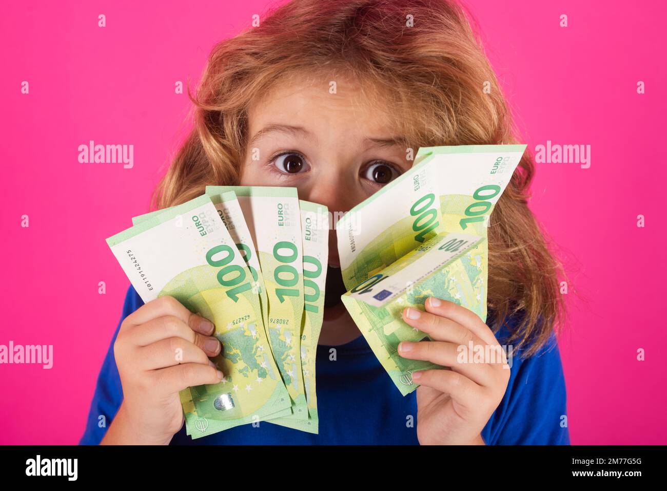 Enfant avec des billets d'argent en euros, debout rêveur de riche sur un arrière-plan isolé de studio. Banque D'Images