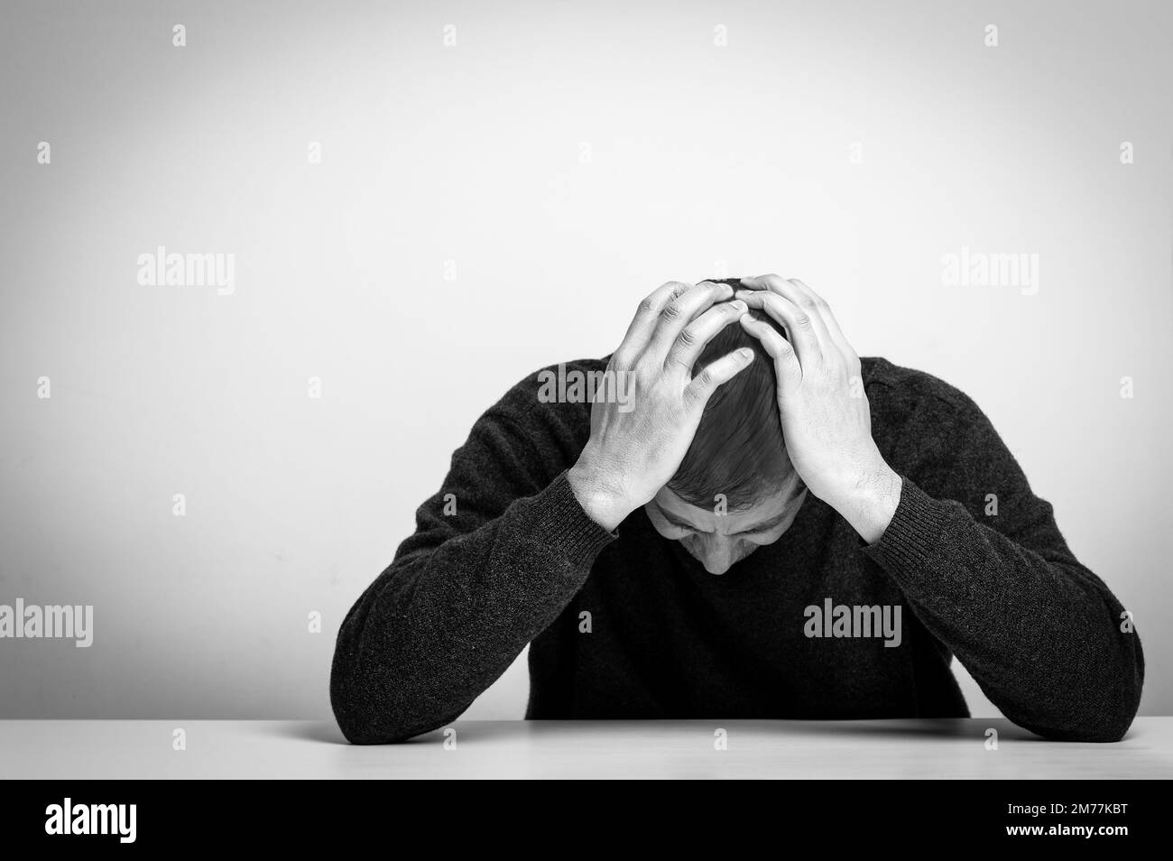 Homme sans-abri addicte de drogue et d'alcool assis seul et déprimé à la maison se sentant anxieux et seul, noir et blanc Banque D'Images