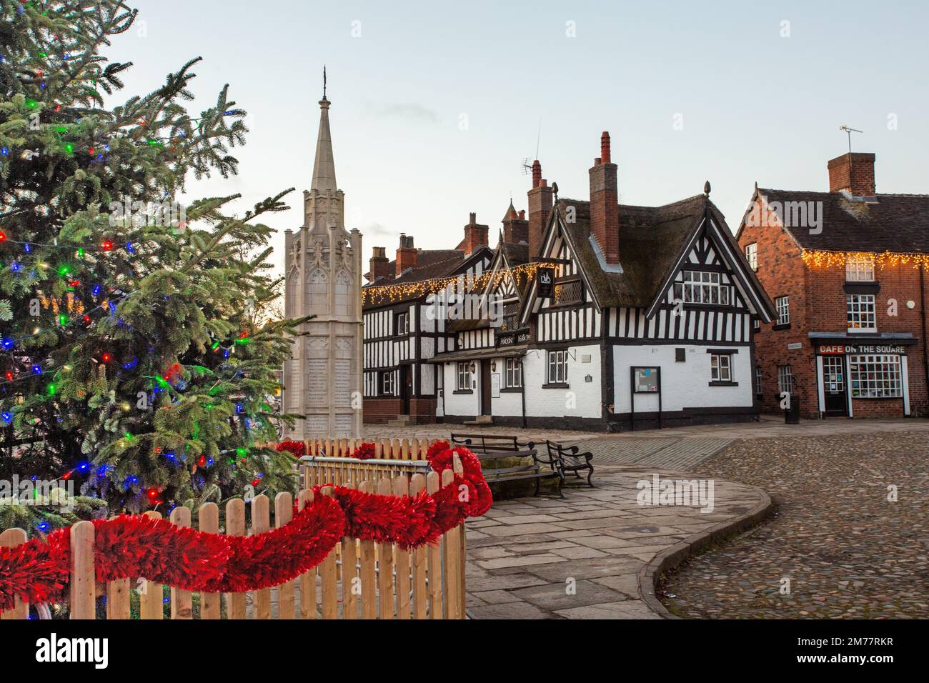 La place du marché pavée de Sandbach à Cheshire avec son arbre de Noël et ses lumières et le mémorial de guerre du cénotaphe et l'auberge de coaching noir et blanc Banque D'Images