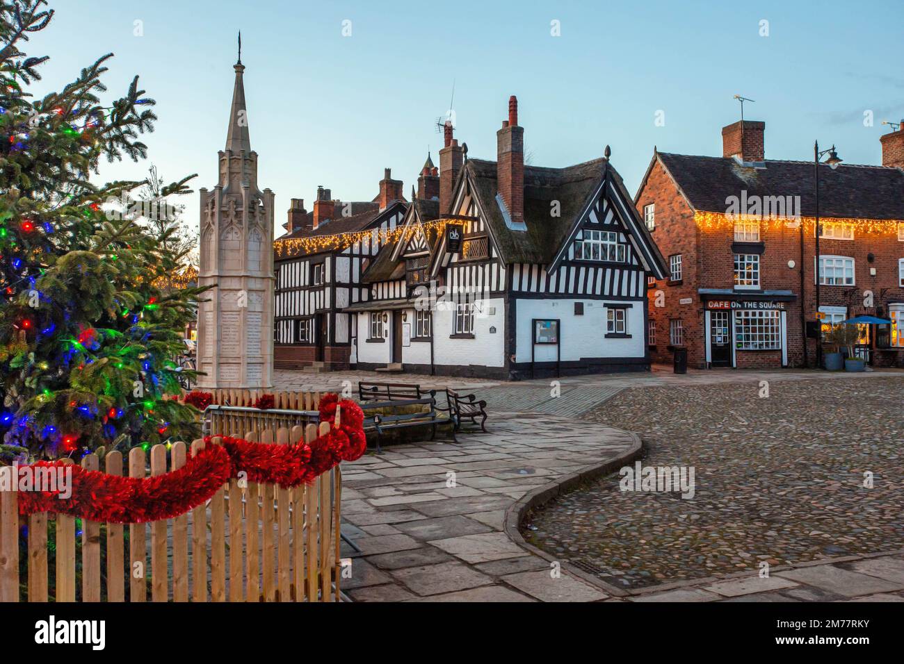 La place du marché pavée de Sandbach à Cheshire avec son arbre de Noël et ses lumières et le mémorial de guerre du cénotaphe et l'auberge de coaching noir et blanc Banque D'Images