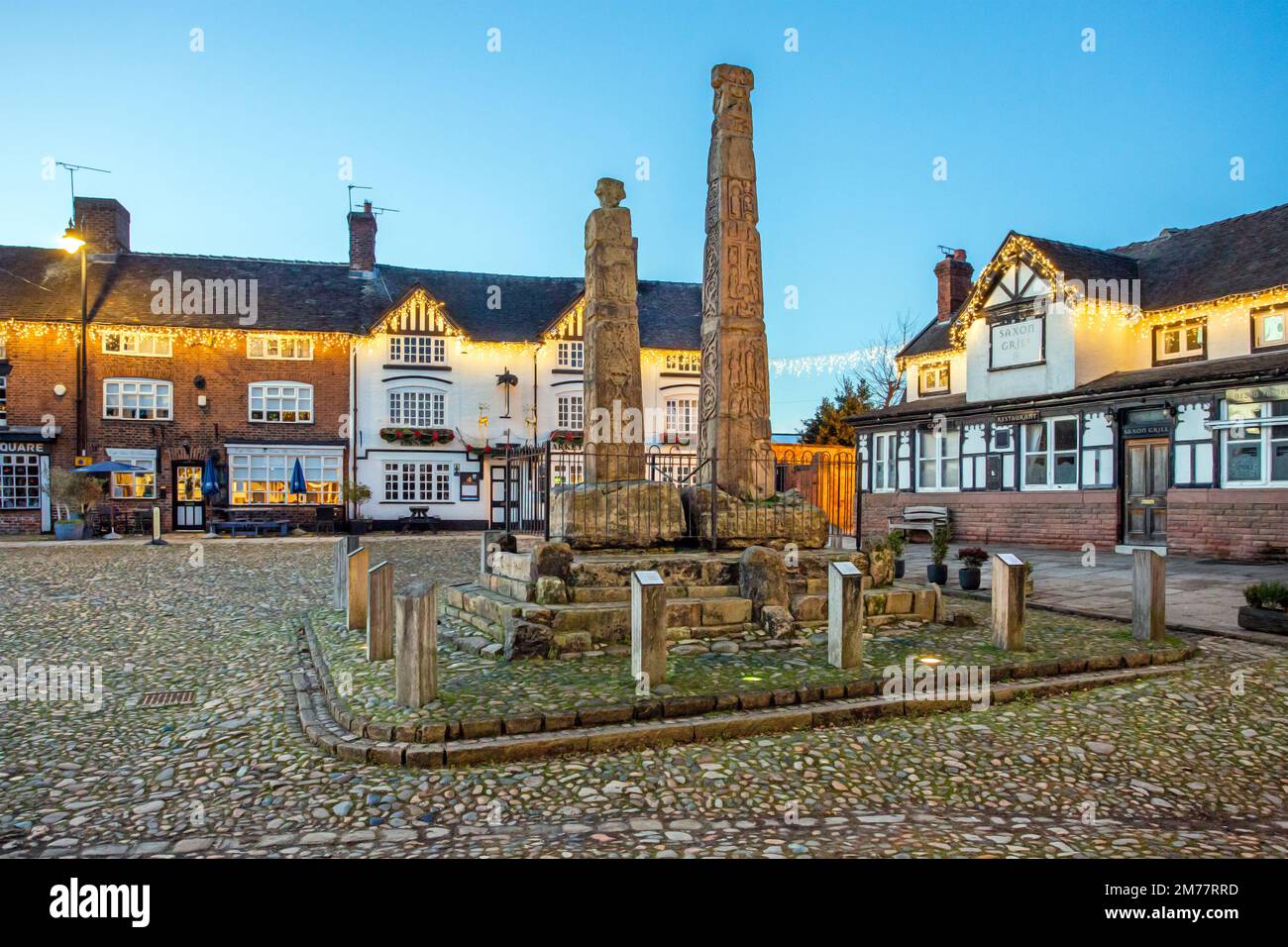 L'ancienne place du marché pavée illuminée dans la ville de Sandbach avec les croix saxonnes et deux vieilles auberges de coaching la nuit Banque D'Images