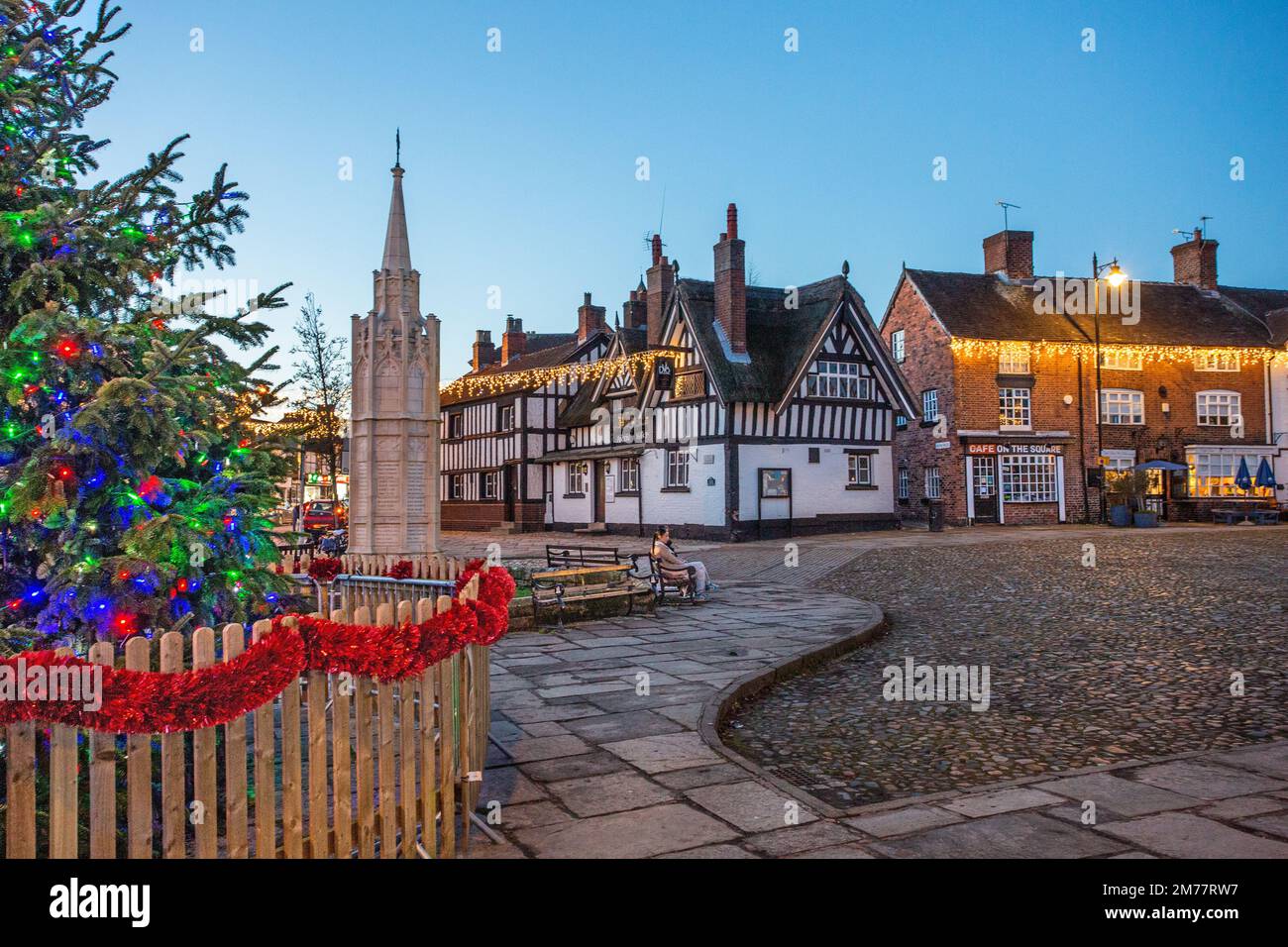 La place du marché pavée de Sandbach à Cheshire avec son arbre de Noël et ses lumières et le mémorial de guerre du cénotaphe et l'auberge de coaching noir et blanc Banque D'Images
