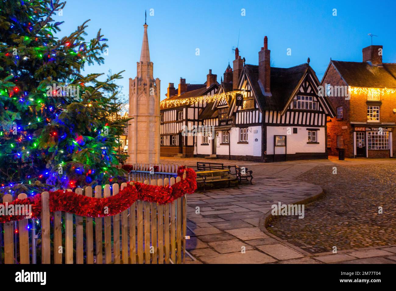 La place du marché pavée de Sandbach à Cheshire avec son arbre de Noël et ses lumières et le mémorial de guerre du cénotaphe et l'auberge de coaching noir et blanc Banque D'Images