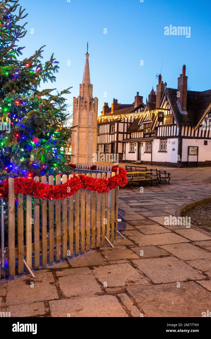 La place du marché pavée de Sandbach à Cheshire avec son arbre de Noël et ses lumières et le mémorial de guerre du cénotaphe et l'auberge de coaching noir et blanc Banque D'Images
