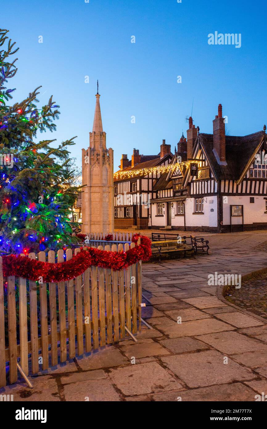 La place du marché pavée de Sandbach à Cheshire avec son arbre de Noël et ses lumières et le mémorial de guerre du cénotaphe et l'auberge de coaching noir et blanc Banque D'Images