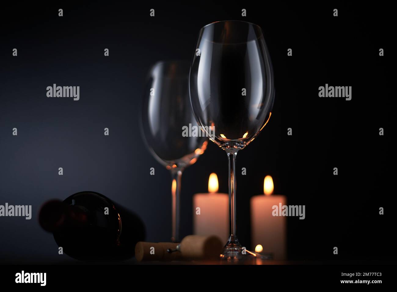 Verre à vin rouge élégant et une bouteille de vin en fond noir Banque D'Images