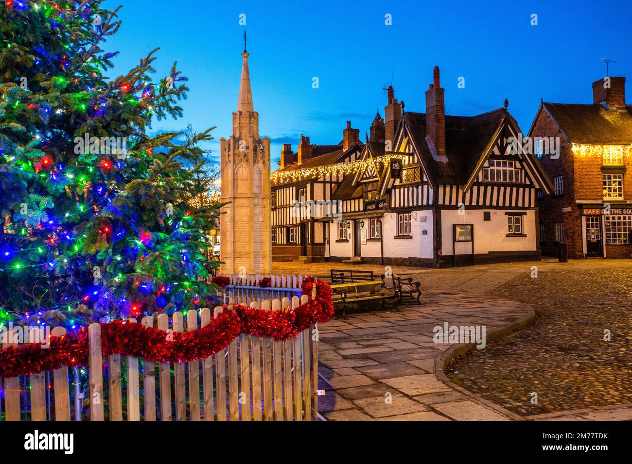 La place du marché pavée de Sandbach à Cheshire avec son arbre de Noël et ses lumières et le mémorial de guerre du cénotaphe et l'auberge de coaching noir et blanc Banque D'Images