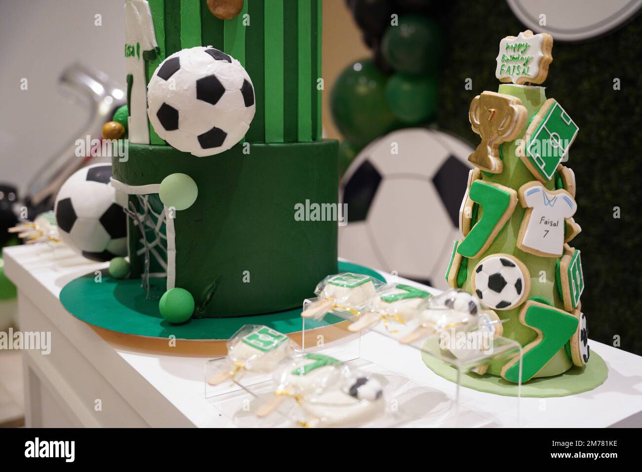 Table de bonbons d'anniversaire de football ou de football décorée de biscuits verts et de petits ballons de football gâteaux pop sur un fond de bannière d'anniversaire. Banque D'Images