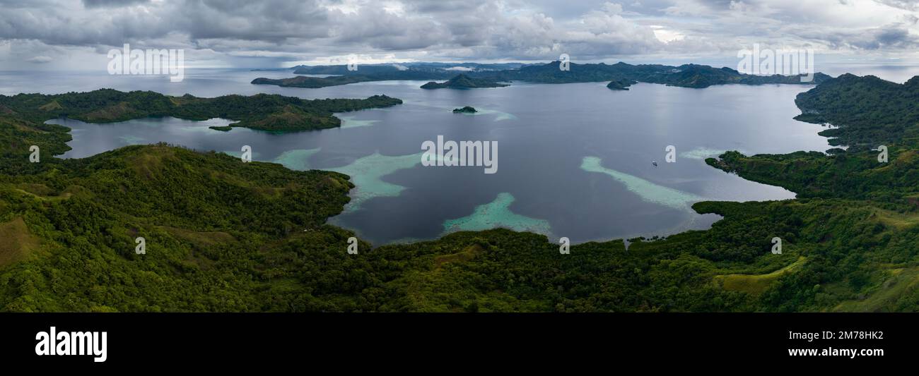 Une île tropicale pittoresque est bordée d'un récif de corail sain dans les îles Salomon. Ce beau pays abrite une biodiversité marine spectaculaire. Banque D'Images