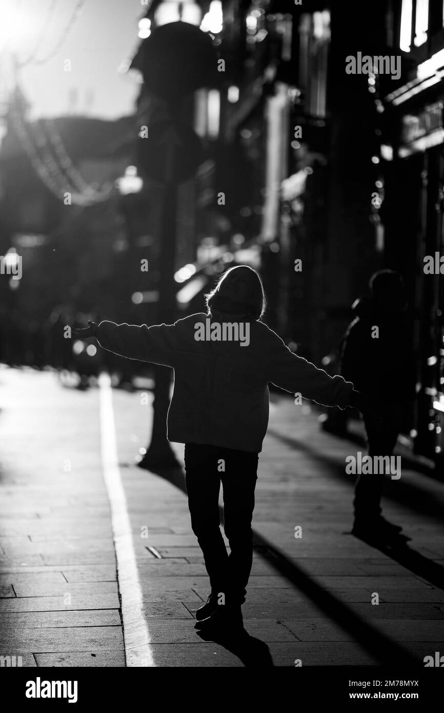 Une femme se tient dans la rue à contre-jour. Photo en noir et blanc. Banque D'Images