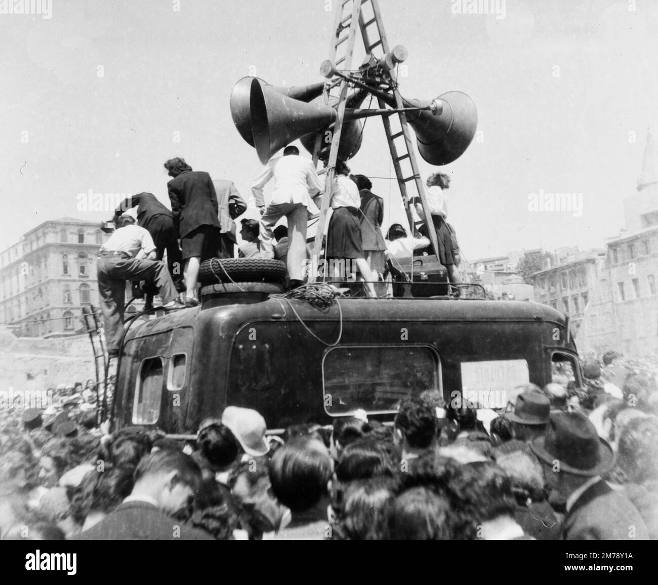 Les foules de célébration et le système de haut-parleurs sur l'avenue la Canabière dans un défilé de victoire, à Marseille, France, le lendemain de la capitulation de l'Allemagne à la fin de la Seconde Guerre mondiale, le 8 mai 1945. Image vintage noir et blanc ou monochrome photographiée le 9 mai 1945. Banque D'Images