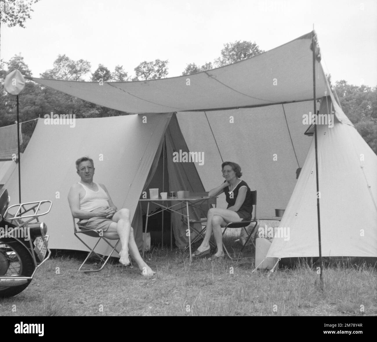 Couple d'âge moyen ou touristes caucasiens Camping en tente Early Ridge sur le camping en France c1960. Photographie noir et blanc ou monochrome vintage. Banque D'Images