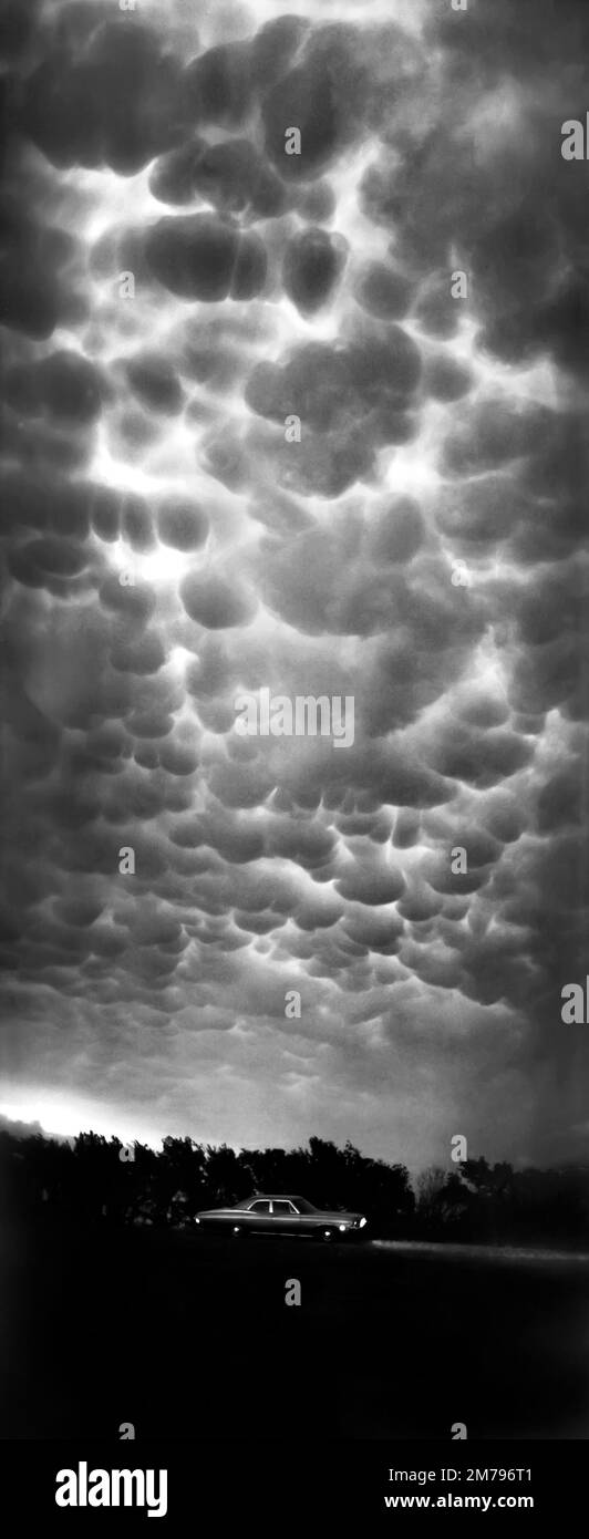 Nuages de Mammatus ou nuage de mammatocumulus la nuit au-dessus d'une voiture de tourisme Chevrolet classique sur l'autoroute 41 au nord de Velva, Dakota du Nord. Orage violent Banque D'Images