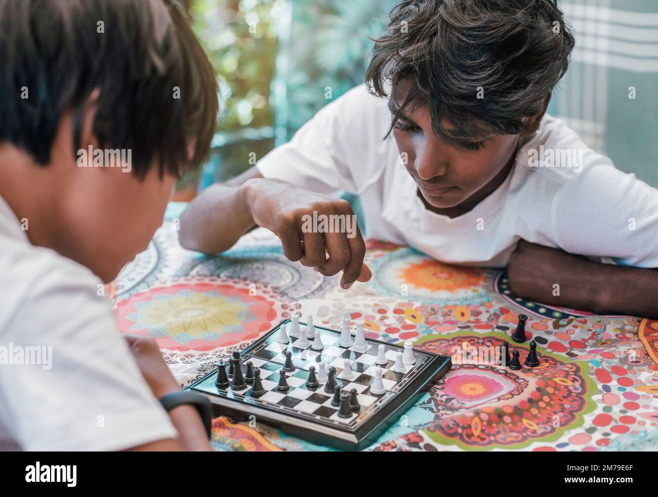vue de dessus de deux garçons multiethniques jouant aux échecs. Les garçons sont d'origine chinoise et indienne. Banque D'Images