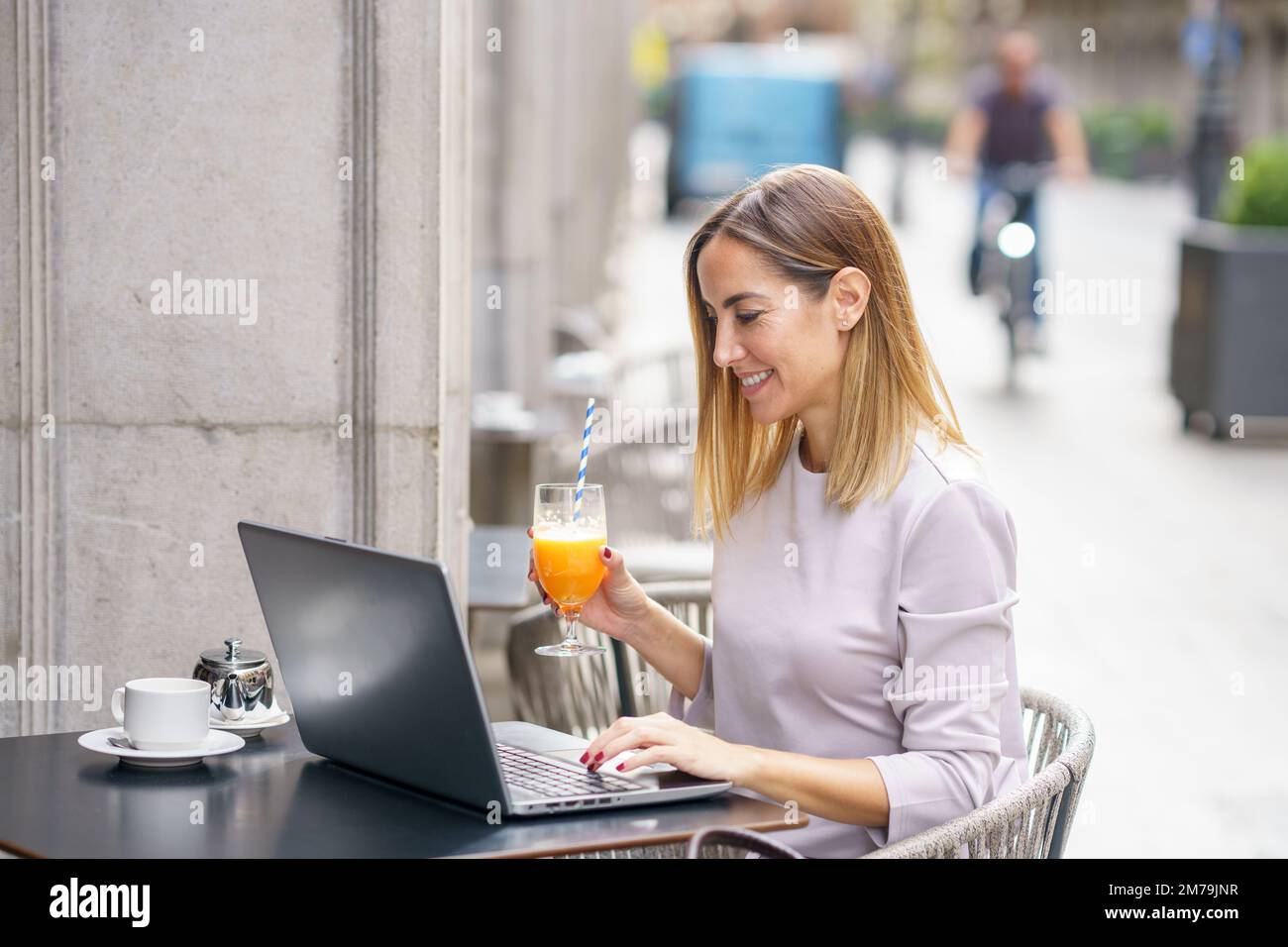 Bonne femme indépendante travaillant sur netbook dans une cafétéria extérieure Banque D'Images