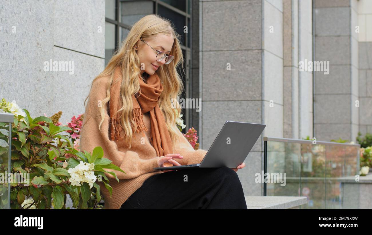 Femme d'affaires attirante réussie travaillant sur un ordinateur portable dans la ville caucasienne fille étudiant e-learning en plein air dame dactylographiant assis sur la terrasse femelle Banque D'Images