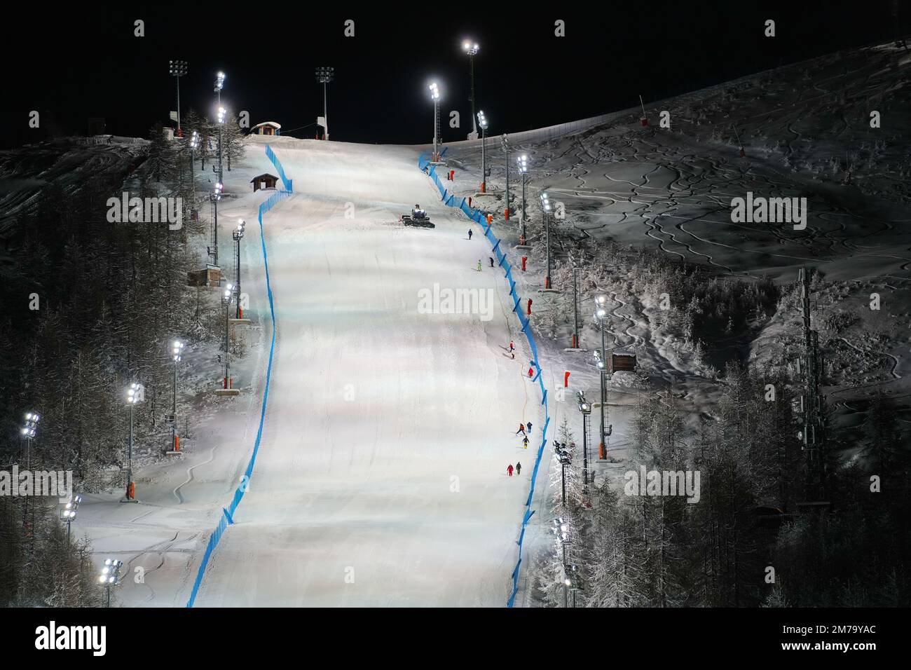 Vue panoramique nocturne sur une piste de ski enneigée éclairée. Service de ski de nuit à la station de montagne d'hiver de Sestriere Banque D'Images