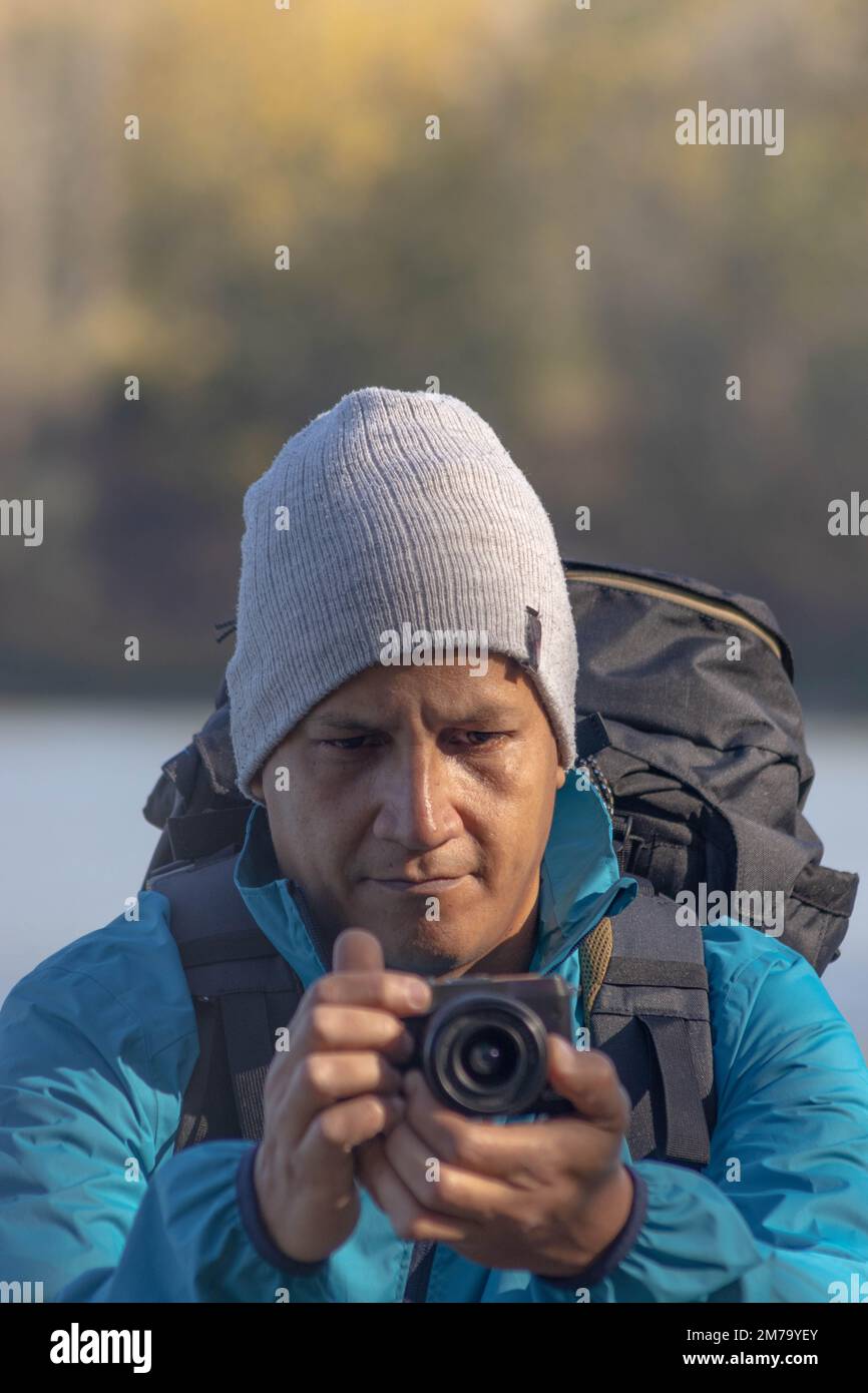 Portrait de voyageur homme au lac en automne prendre une photo avec l'appareil photo numérique Banque D'Images