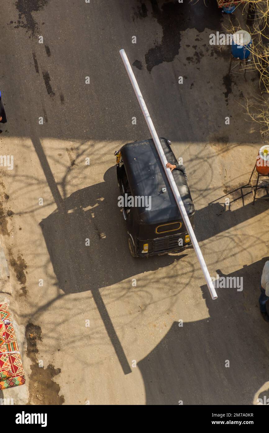 Vue aérienne d'un tuk-tuk transportant un long tuyau au Caire, Égypte Banque D'Images