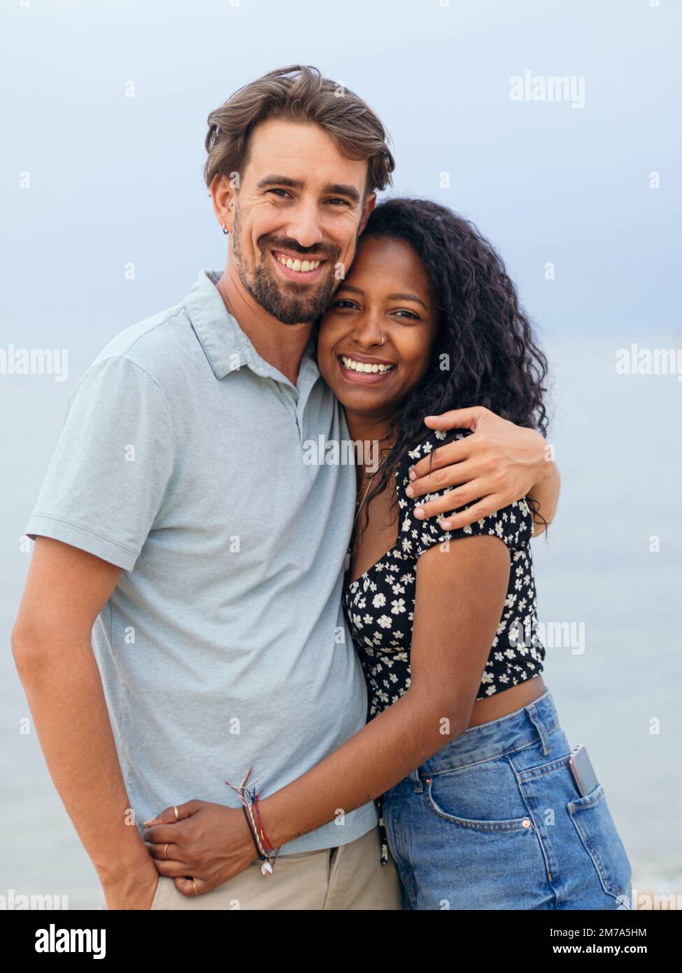 Jeune couple hétérosexuel souriant et enveloppant regardant la caméra. Concept de lune de miel, jour de la Saint-Valentin Banque D'Images