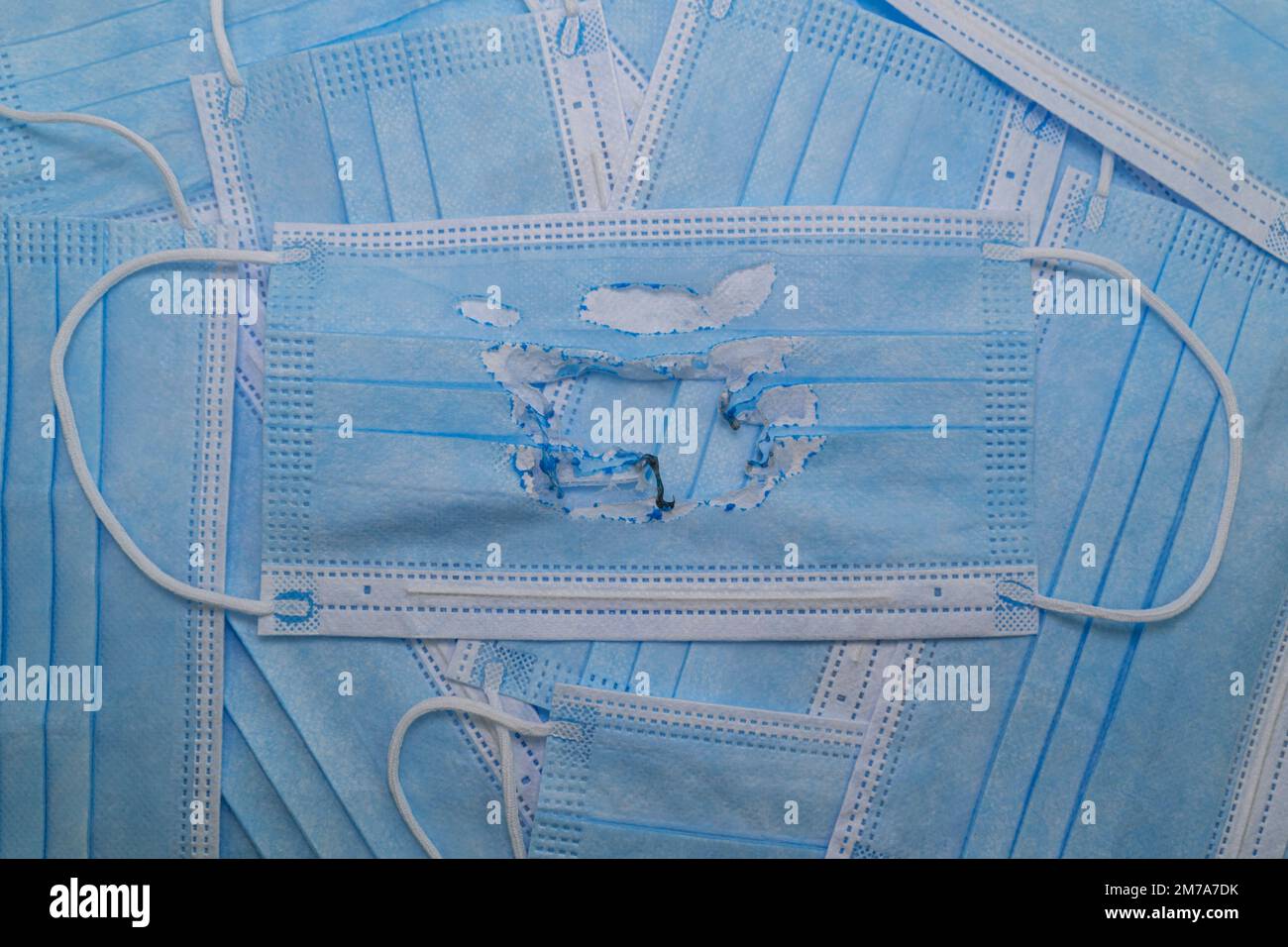 Utilisé (brûlé) masque médical bleu sur le fond de nouveaux masques (non utilisés). Le concept de la fin de la pandémie. Annuler le mode masque. Zéro covi Banque D'Images